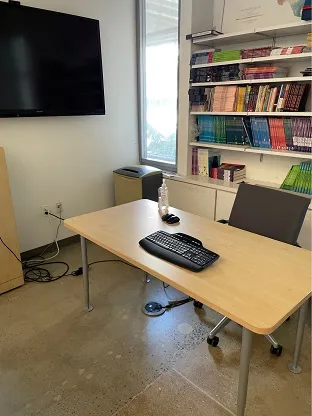 rectangular conference table with a single desk chair and computer mounted on wall